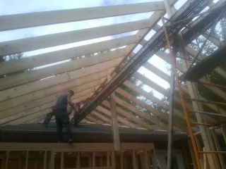 Rafters going up over a new addition with a worker on the wall in Fort Scott