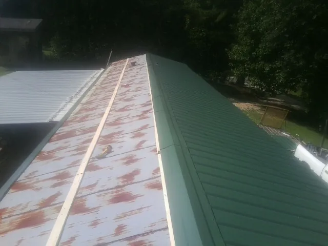 Old rusted panels beside newly installed green metal roofing — Wind Damage Roof Repair by Roofing Brothers in Fort Scott