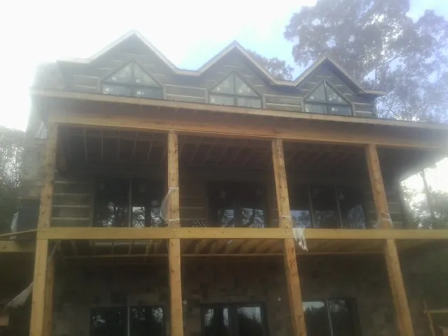 Dormers and porch framing on a large log home under construction — Roof Coating work by our crew in Fort Scott