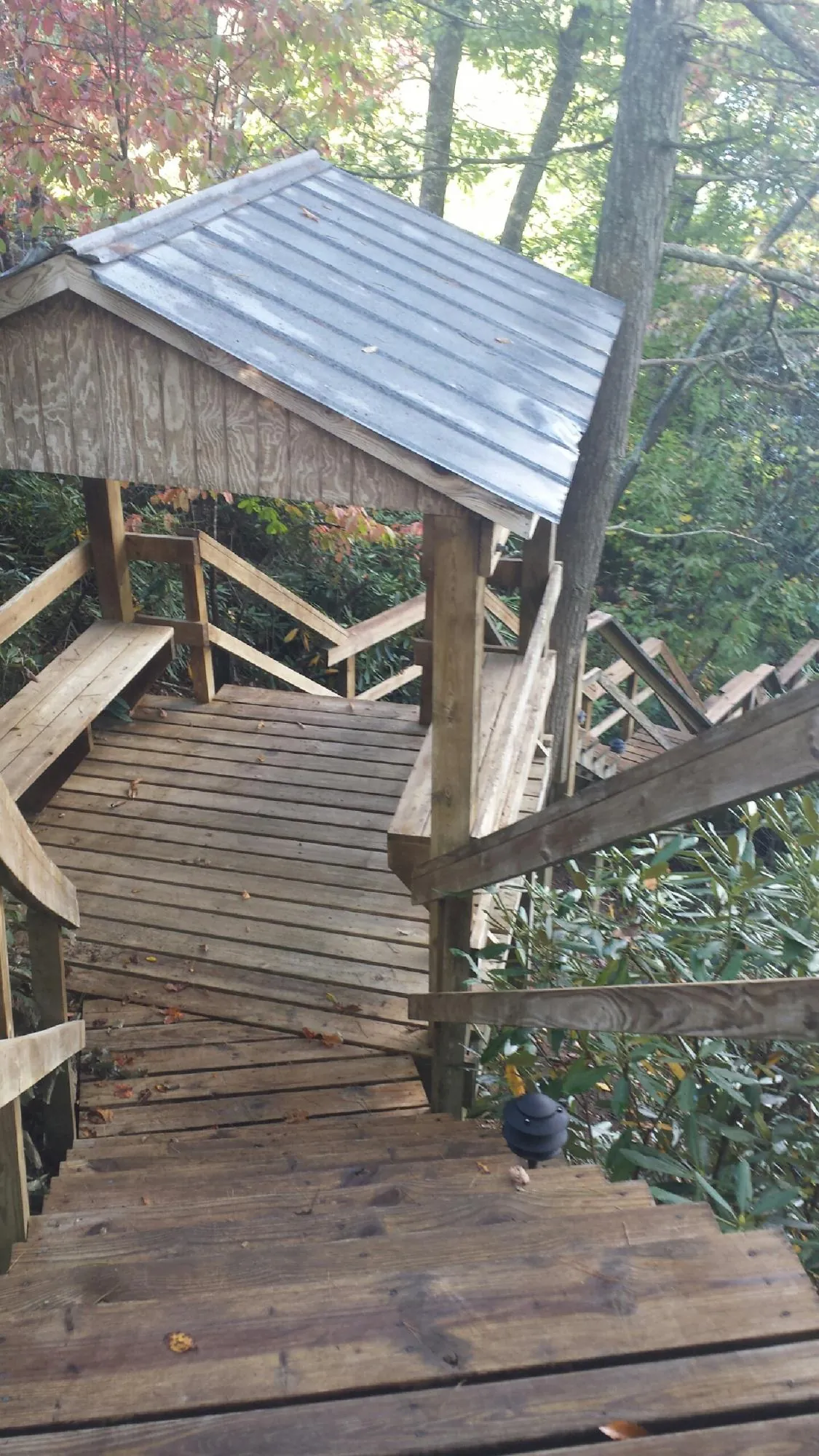 Metal roofed shelter over wooden steps on a wooded walkway — Skylight Repair & Installation work by our crew in Fort Scott