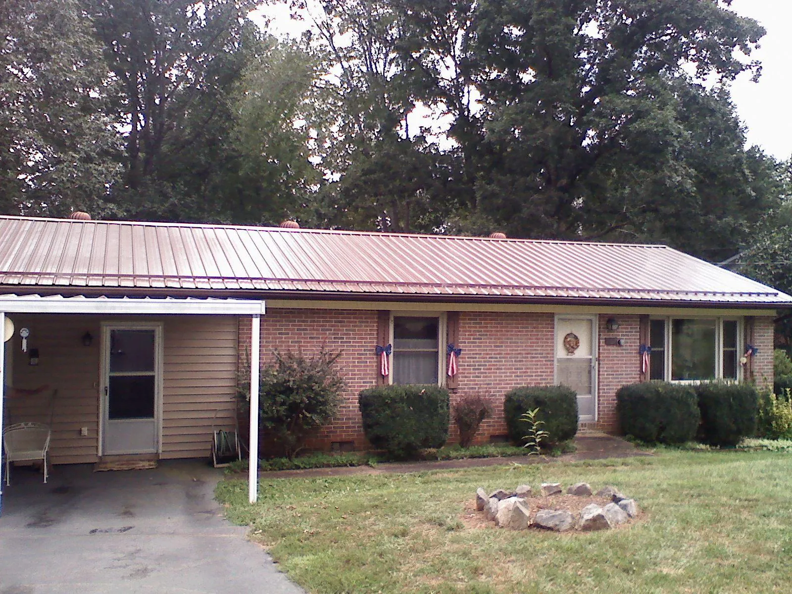 Bronze metal roof and carport on a brick ranch home — Roof Repair work by our crew in Fort Scott