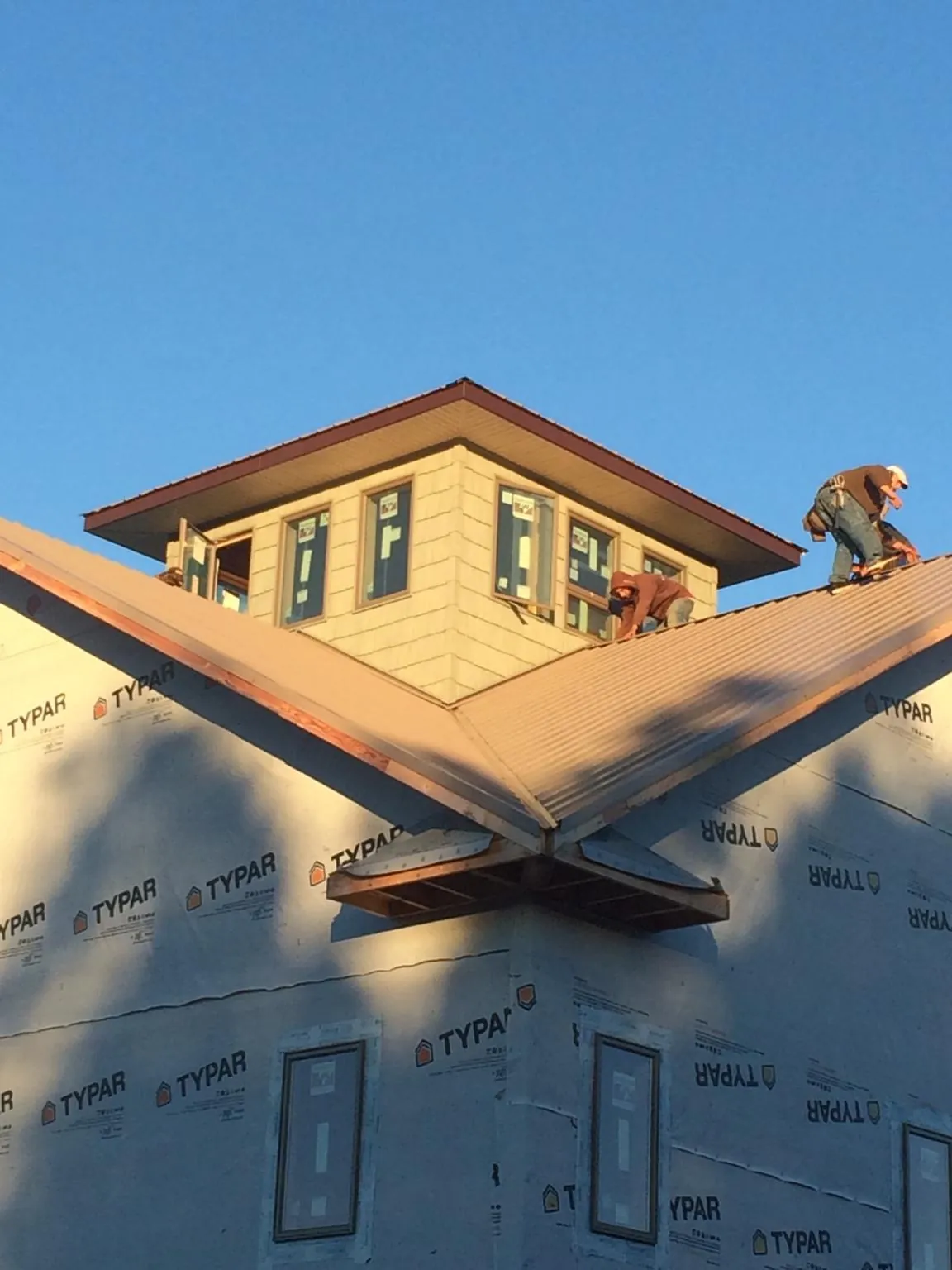 Roofers working around a rooftop cupola on a new metal roof at sunset — Roof Waterproofing in Fort Scott by Roofing Brothers